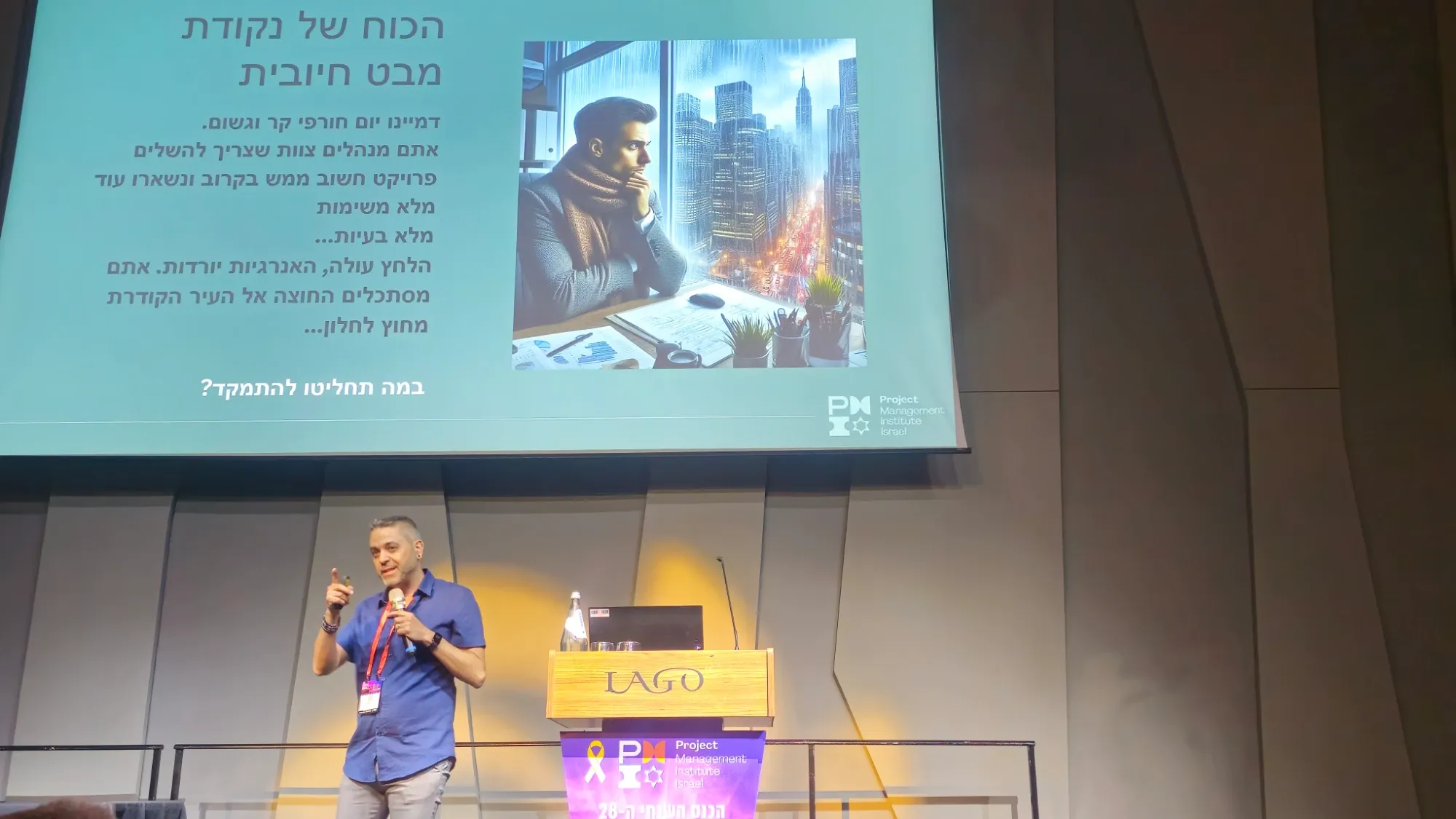 עזר סלם מרצה על במה בכנס, מתחת לשקף "הכוח של נקודת מבט חיובית"